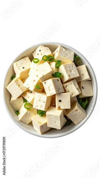 Fototapeta Cubes of light-colored,  cubed cheese in a white bowl.  Fresh green onions sprinkled on top.  High-angle view