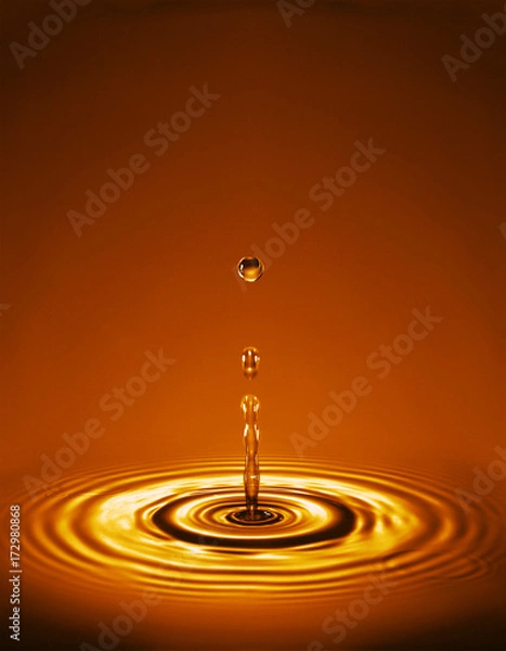 Obraz Droplet with ripples in gold amber liquid