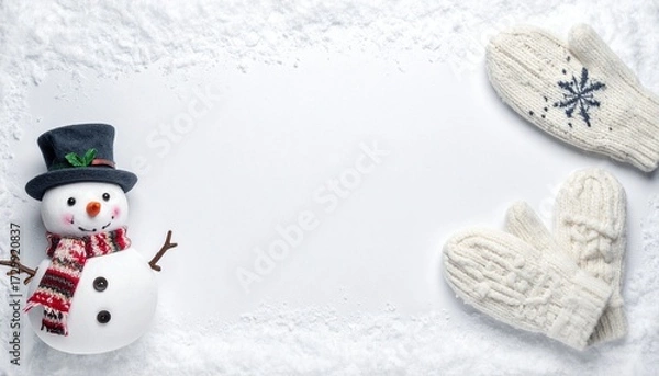 Fototapeta Snowman with a scarf and hat next to a pair of mittens on a snowy background.