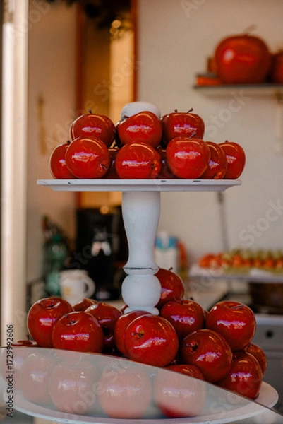 Fototapeta Candied red apples on white stand. Red candied apples displayed on a white stand at a festive market, symbolizing traditional sweet dessert and celebration treats