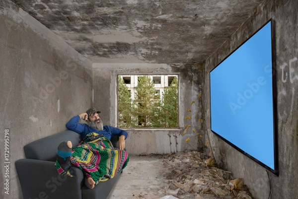 Fototapeta Bearded man lying on couch in abandoned room and watch TV on wall with blue screen