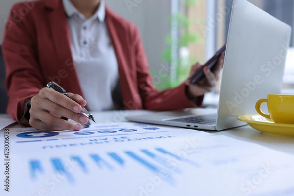 Obraz Hand of businesswoman holding a pen, discussing marketing analytics at the office.