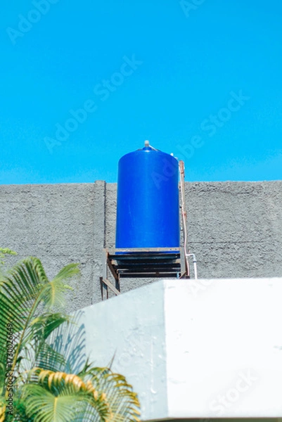 Fototapeta Blue water tank installed on top of a building, in a concrete structure. Reservoir used for storing water.