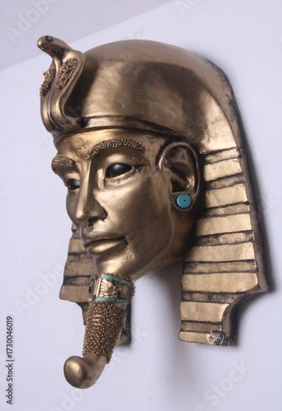 Fototapeta Golden pharaoh mask sculpture with turquoise accents, featuring alien-inspired eyes. A mysterious blend of ancient Egyptian symbolism and cosmic allure. Unique contemporary sculpture.