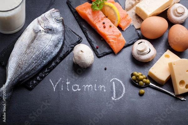 Fototapeta Czarny stół łupkowy z produktem bogatym w witaminę D i omega 3. Witamina D zapisana białą kredą.