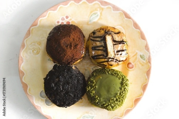Fototapeta Top view of assorted sweet donuts with colorful toppings on a decorative ceramic plate