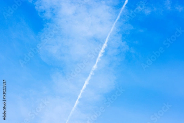 Fototapeta Beautiful clear blue sky with white airplane contrail line on background of light clouds.