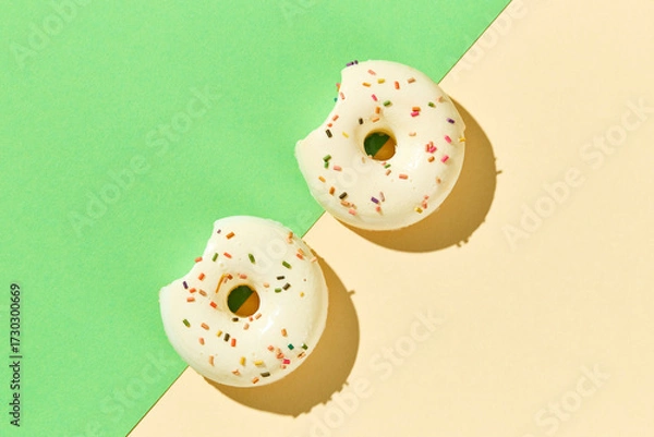 Fototapeta Overhead view of various donuts with confetti arranged on colored background