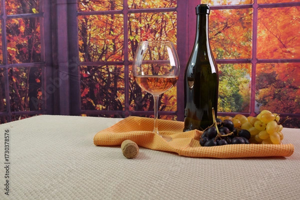 Fototapeta Tavola con bottiglia, calice di vino rosè e uva