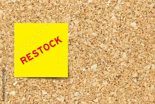 Fototapeta Yellow note paper with word restock on cork board background with copy space