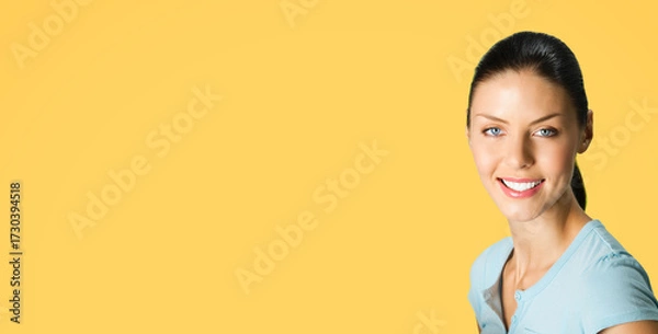Fototapeta Portrait image of young happy smiling cute brunette woman wear blue casual clothing, posing at studio, isolate yellow color background, with free space blank text area