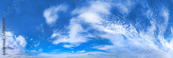 Fototapeta White high-altitude clouds almost completely obscure blue sky. Light vapor appears against blue background. Arch cirrus clouds curves cloudscape panoramic across wide field view atmospheric spectacle.
