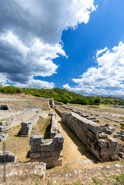 Fototapeta Ancient Roman ruins standing under large clouds in L'Aquila
