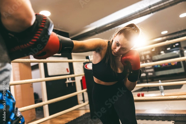 Fototapeta Boxing training session featuring a woman sparring in a modern gym in the afternoon