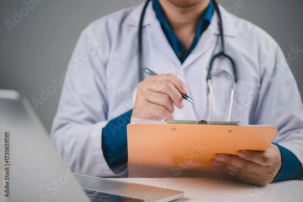 Obraz Healthcare and medicine concept. Physician writing on medical chart for patient examination results. Doctor documenting information for insurance claim, diagnosis, or treatment protocol in a clinic.