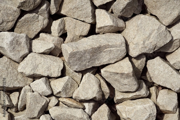 Fototapeta Various sizes of light-colored gravel stones pile up in an outdoor setting under bright natural light