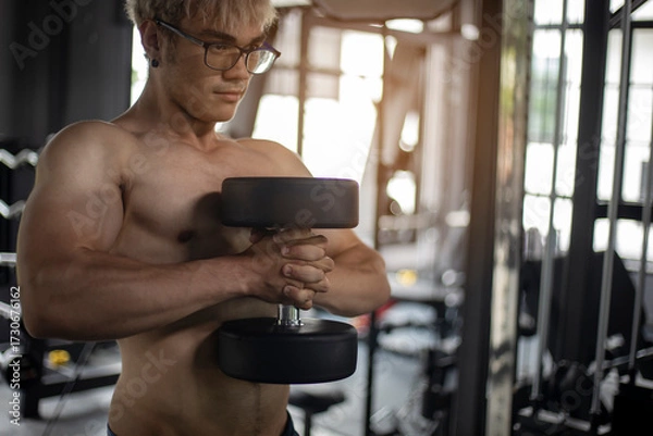 Obraz Athletic shirtless handsome young man, muscular young men are exercising with weights in a gym.

