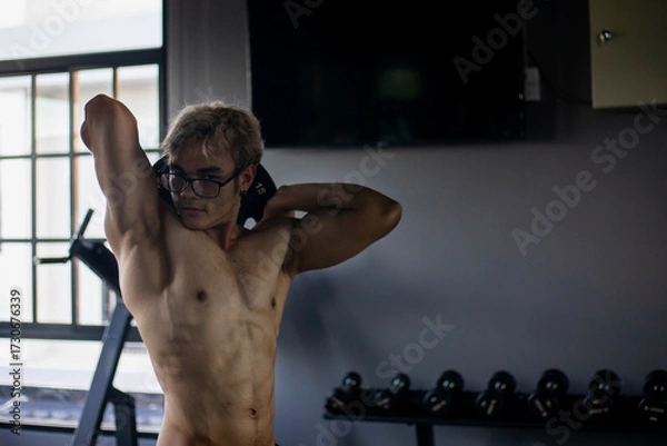 Obraz Athletic shirtless handsome young man, muscular young men are exercising with weights in a gym.
