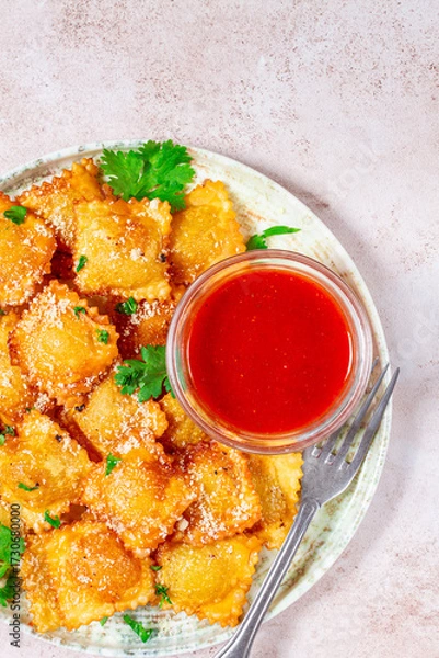 Obraz fried ravioli with parmesan cheese, served with red sauce and garnished with herbs, on a light background, no people,