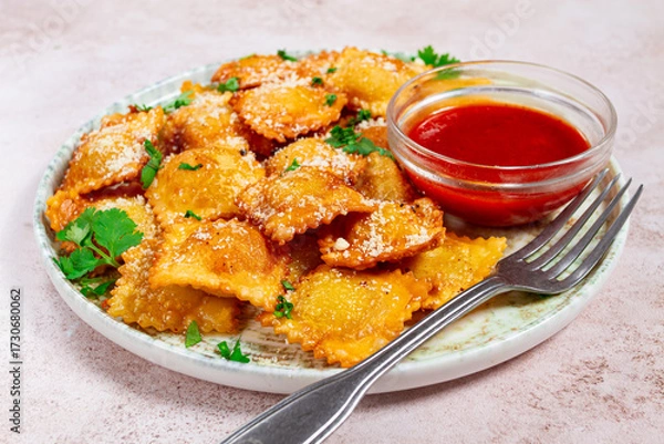Obraz fried ravioli with parmesan cheese, served with red sauce and garnished with herbs, on a light background, no people,