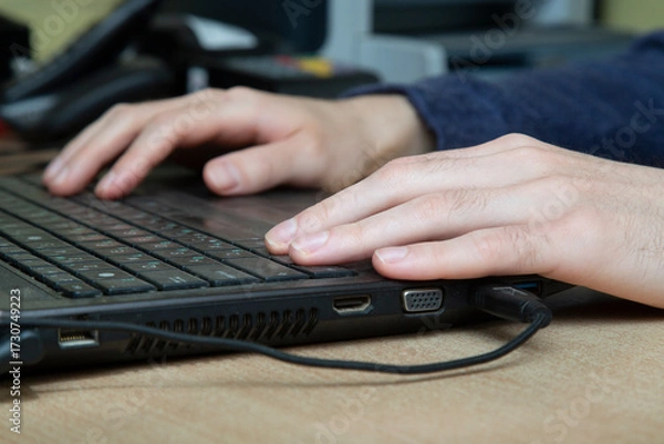 Fototapeta A man is working on a laptop. His hands are on the keyboard.