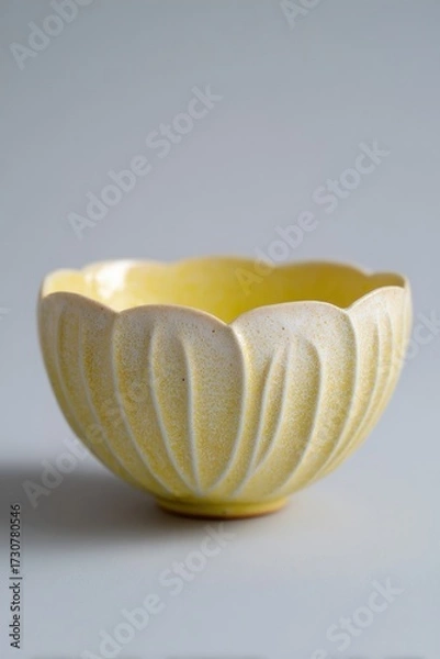 Fototapeta Yellow ceramic bowl with petal motif and textured surface, showcasing intricate design and craftsmanship, perfect for decorative or functional use in various settings