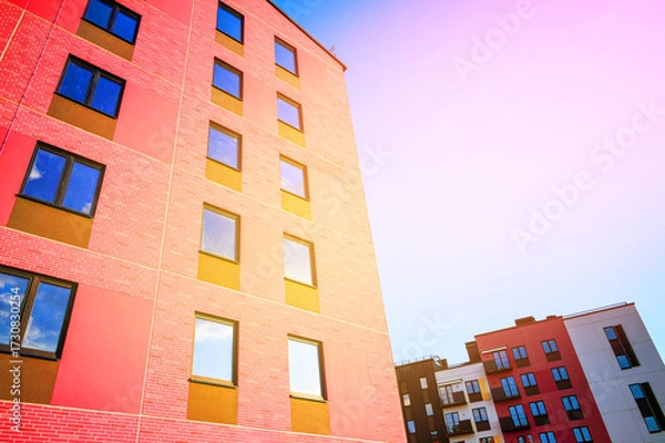 Fototapeta Brightly Colored Modern Buildings Under Clear Sky During Day Showcasing Urban Architecture Design. Modern facade building close-up. Two modern residential buildings feature bright colors.