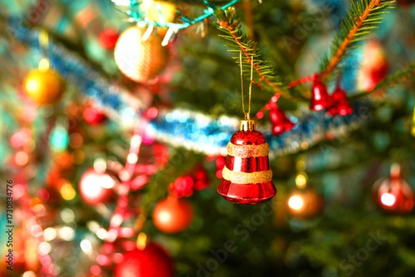 Fototapeta Christmas tree adorned with shiny lights in New Year. Bright Red Ornament Hanging on Christmas Tree With Colorful Decorations in Festive Setting. Vibrant red ball, ornament dangles on fir-tree.