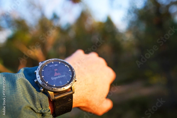 Fototapeta Person Check Hiking Watch in Forest Late Afternoon, Capturing Essence of Outdoor Adventures. Expedition Adventure, Hiking Watch on Forest Background. Adventure Watch Displayed on Wrist in Forest.