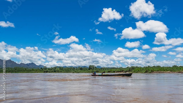 Fototapeta Heavy rain over the Amazon River and forest, with a small boat navigating the water amidst the storm
