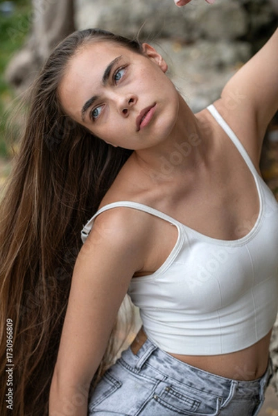 Obraz Young beautiful woman in a white top posing on rocks in the mountains