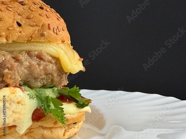 Fototapeta A large cheeseburger with tomatoes and greens on a white plate. Delicious, nutritious, and quick food.