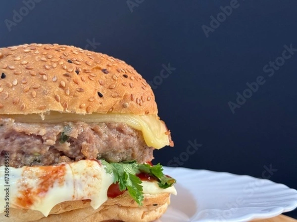 Fototapeta A large cheeseburger with tomatoes and greens on a white plate. Delicious, nutritious, and quick food.