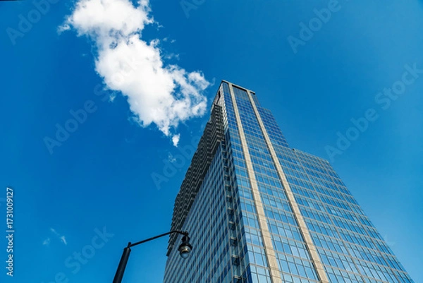 Obraz Modern skyscraper reflecting the vibrant blue sky. Perfect for corporate or architectural themes.
