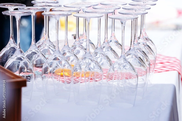 Fototapeta Stacked wine glasses arranged neatly on a table with a red and white checkered tablecloth, showcasing elegance and preparation for a gathering or event