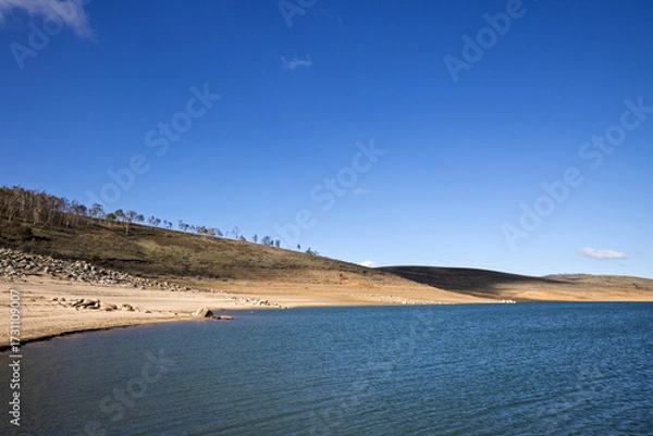 Fototapeta Tree-lined hills roll down to the clear waters of Lake Eucumbene in the Snowy Mountains of NSW, Australia. This alpine lake is regarded as a premier trout fishing location.