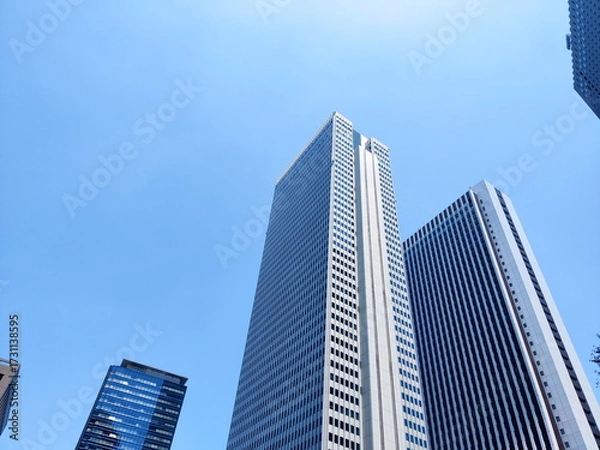 Fototapeta 快晴の青空を背景に東京都新宿区の超高層ビル群を下から見上げるように捉えた写真無機質で巨大な現代建築の構造が強調されている