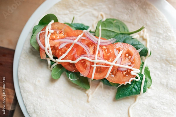 Fototapeta Top down view of salad wrap in preparation with tomato, spinach, red onion and mayonnaise