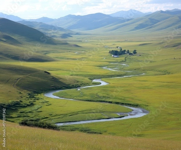 Fototapeta Serene winding river meanders through vast green valley under rolling mountains and clear sky