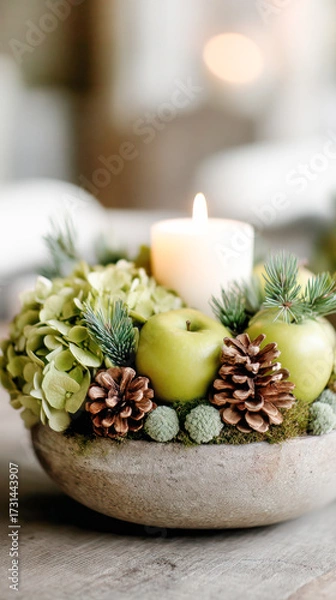 Fototapeta Decorative arrangement featuring green apples, pine cones, and hydrangeas in a rustic bowl with a lit candle creating a warm ambiance for home decor