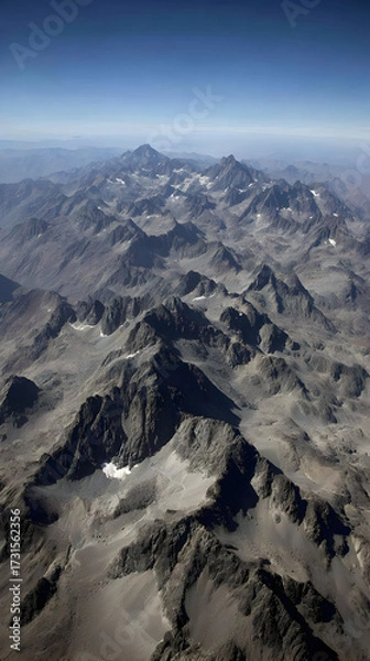 Fototapeta terrain with rugged peaks and valleys under a clear sky casting dramatic shadows and highlights