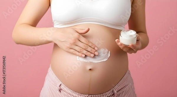 Fototapeta Pregnant woman applying cream on her belly to prevent stretch marks, promoting healthy pregnancy and skincare with soft touch and care