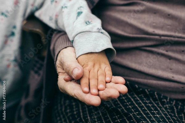 Fototapeta Close-up of a child s hand resting on top of an elderly person s hand. Symbol of care, family connection, support, generations, love, and togetherness.