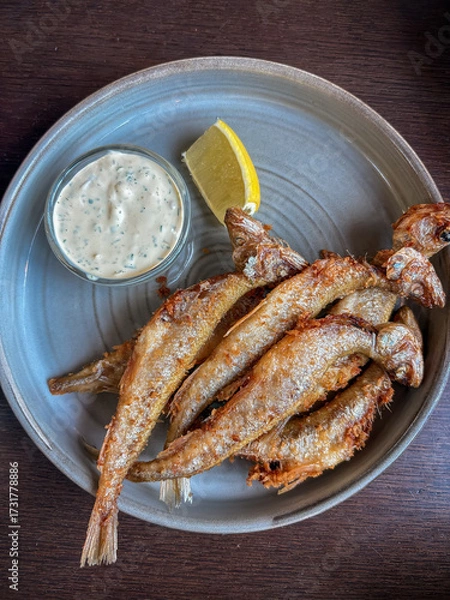 Fototapeta Crispy deep-fried smelt fish served with a creamy tartar sauce and fresh lemon