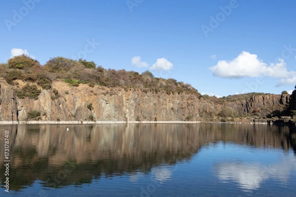 Fototapeta Natural feature: remnants of open quarry created a stunning large water pool. The towering sandstone formations showcase industrial heritage at Prestonhill Quarry, Inverkeithing, Fife, Scotland.

