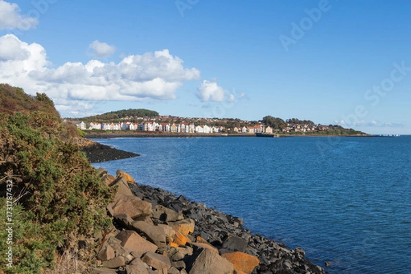 Fototapeta A tranquil view of the Dalgety Bay coastline, Fife, Scotland, featuring the calm waters meeting the rocky shore. The image captures the peaceful ambience of this Scottish coastal town.