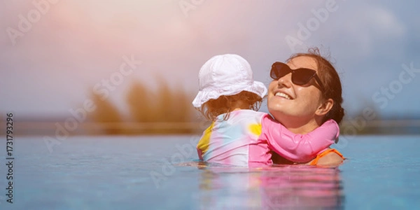 Obraz Mother and daughter embracing in infinity pool at tropical resort
