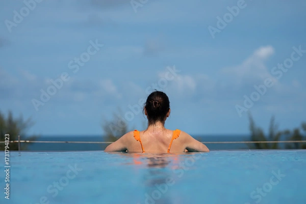 Obraz Tourist relaxing in infinity pool enjoying ocean view