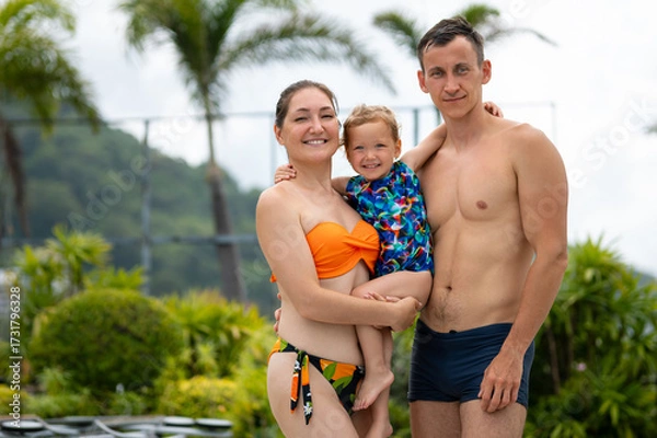 Obraz Happy family posing together by hotel poolside