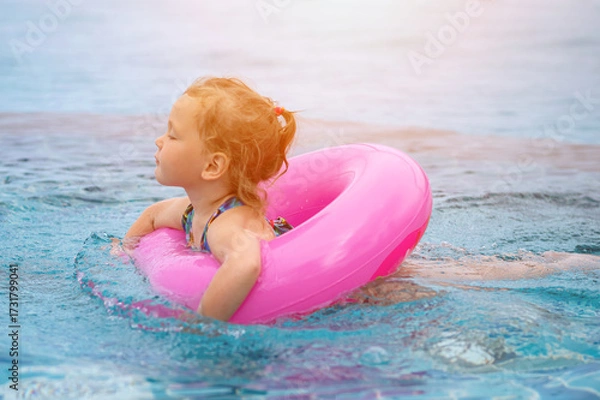Obraz Little girl relaxing on pink inflatable ring in swimming pool